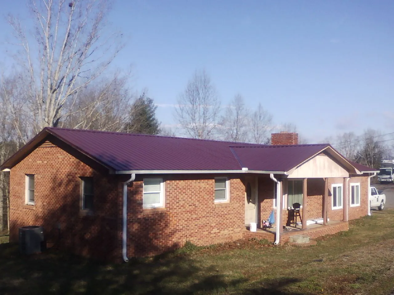 Burgundy metal roof on a brick ranch home with a new addition in Danbury